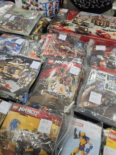 Used LEGO sets in sealed bags on a trader's table, each with a handwritten price label